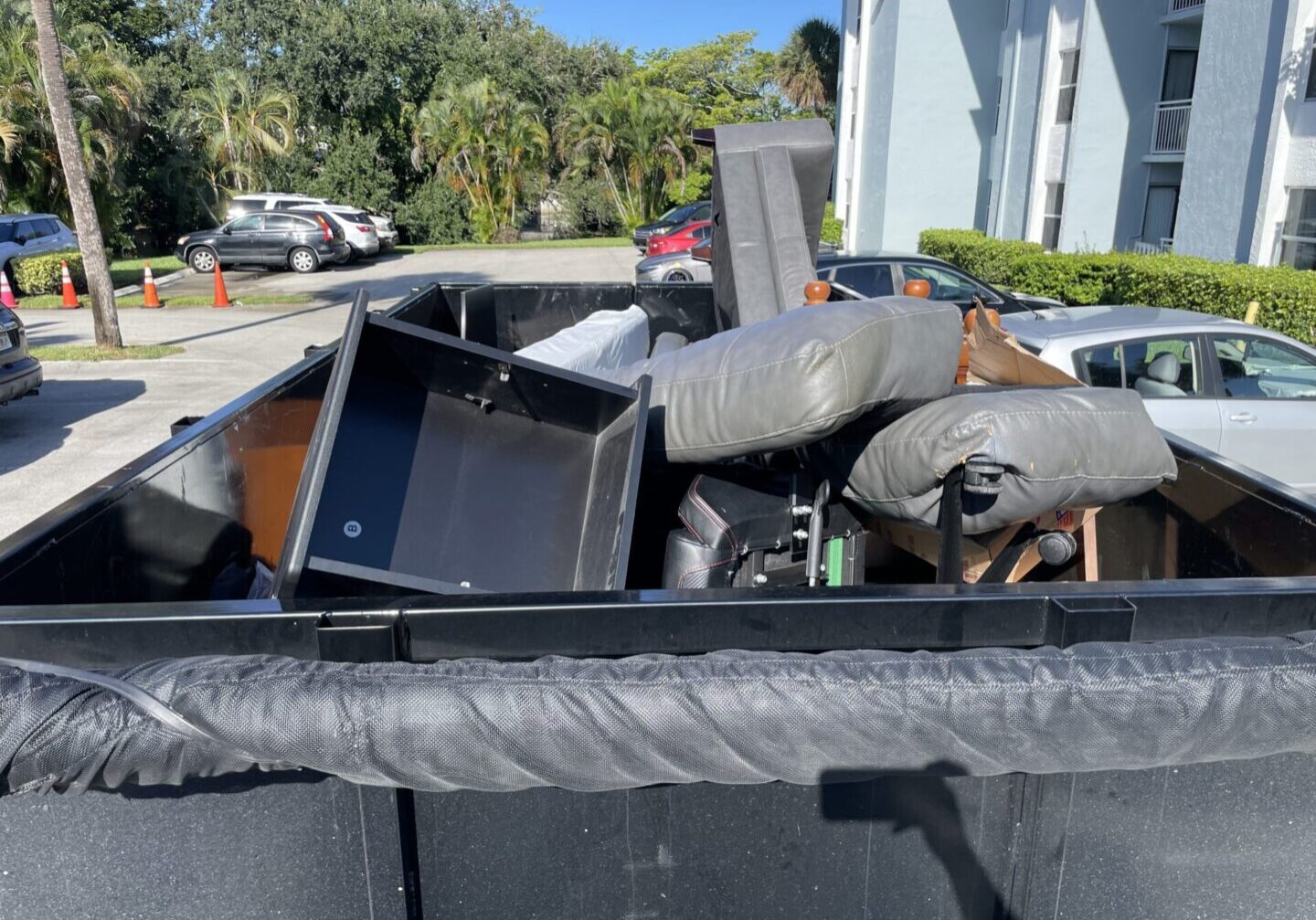 A dumpster full of junk sitting next to a building.